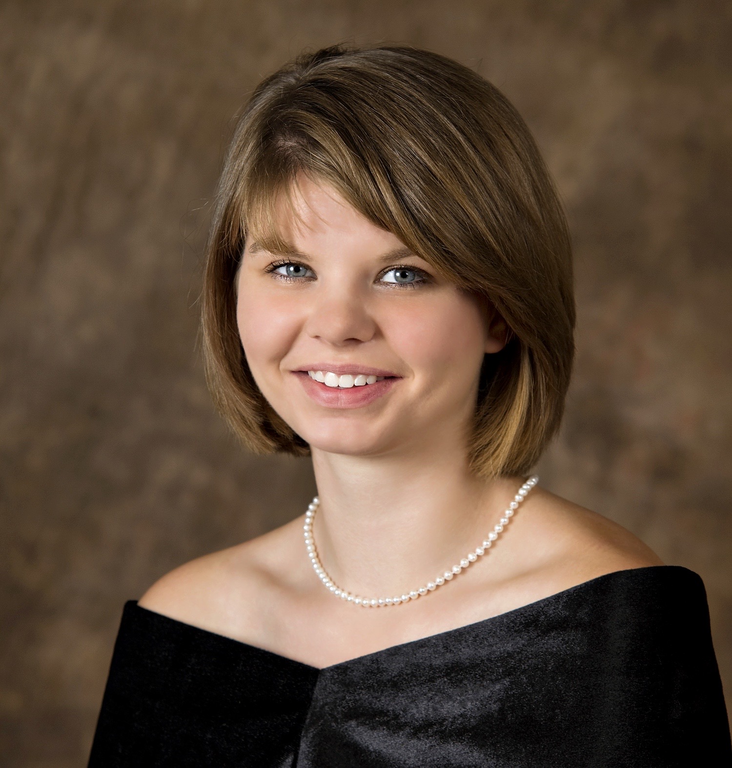 Seen here is a 19 year old young lady sitting for her High School Senior portrait wearing a traditional simple black drape and pearls. Head straight.See other related images here: