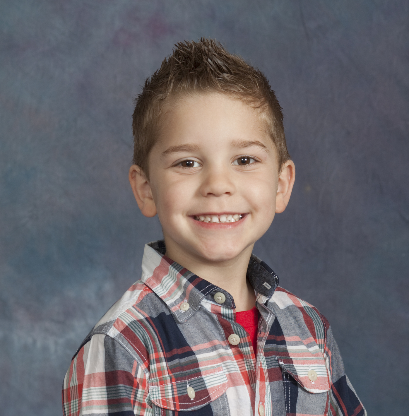 Portrait of a four-year-old boy with against a studio background. Model is smiling and quite happy. Standing