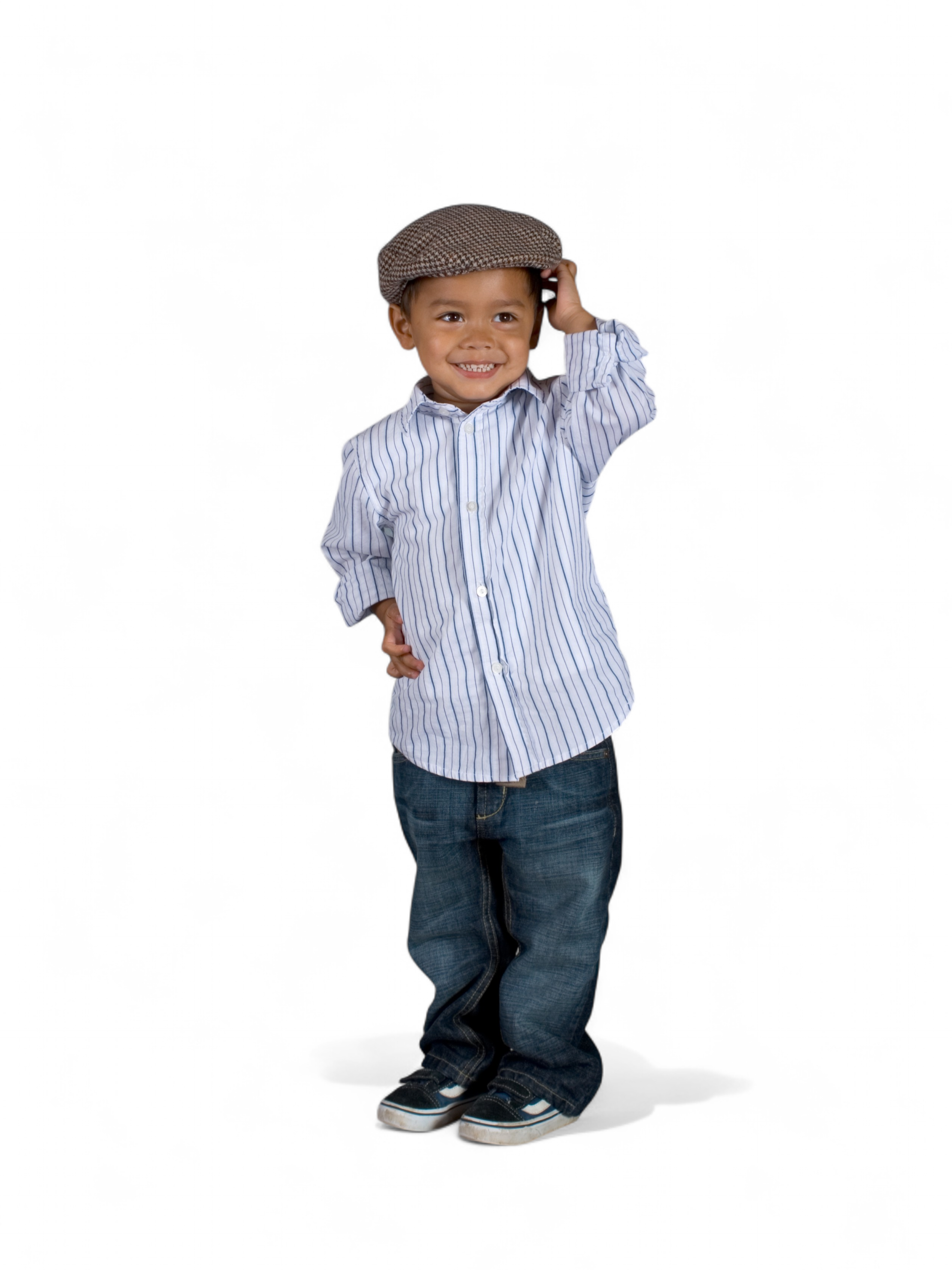 A young boy stands smiling, wearing a striped button-up shirt, blue jeans, trainers, and a brown flat cap—one hand touching the cap—as if ready to explore an API Playground, all against a plain white background.